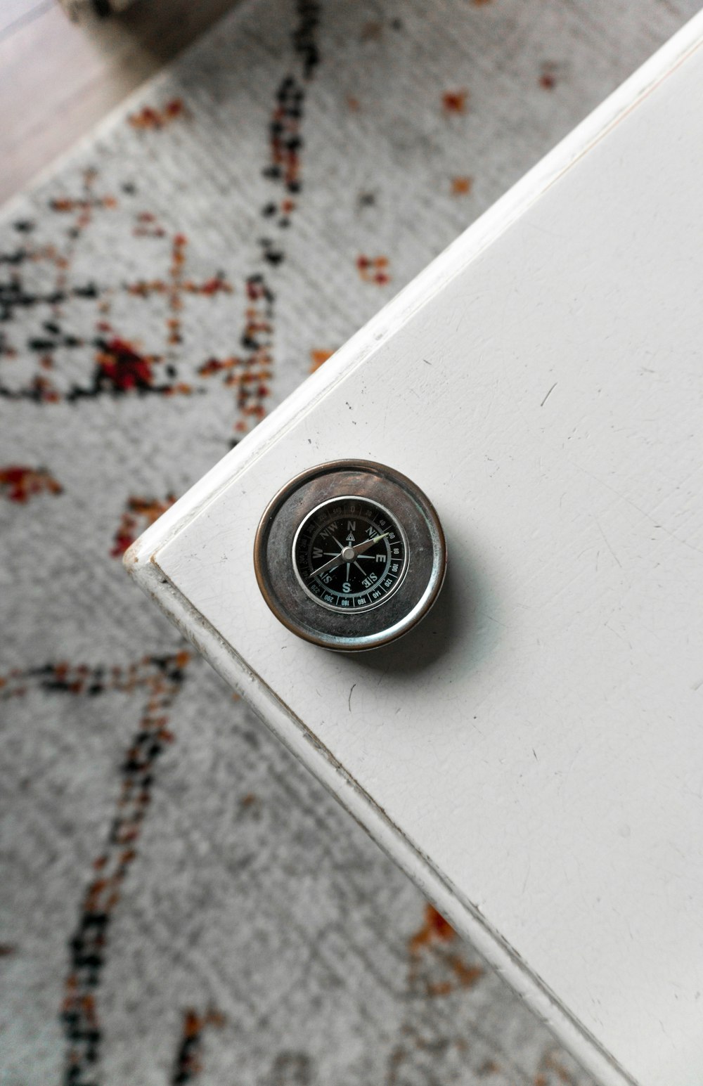 silver-colored compass on edge of white table