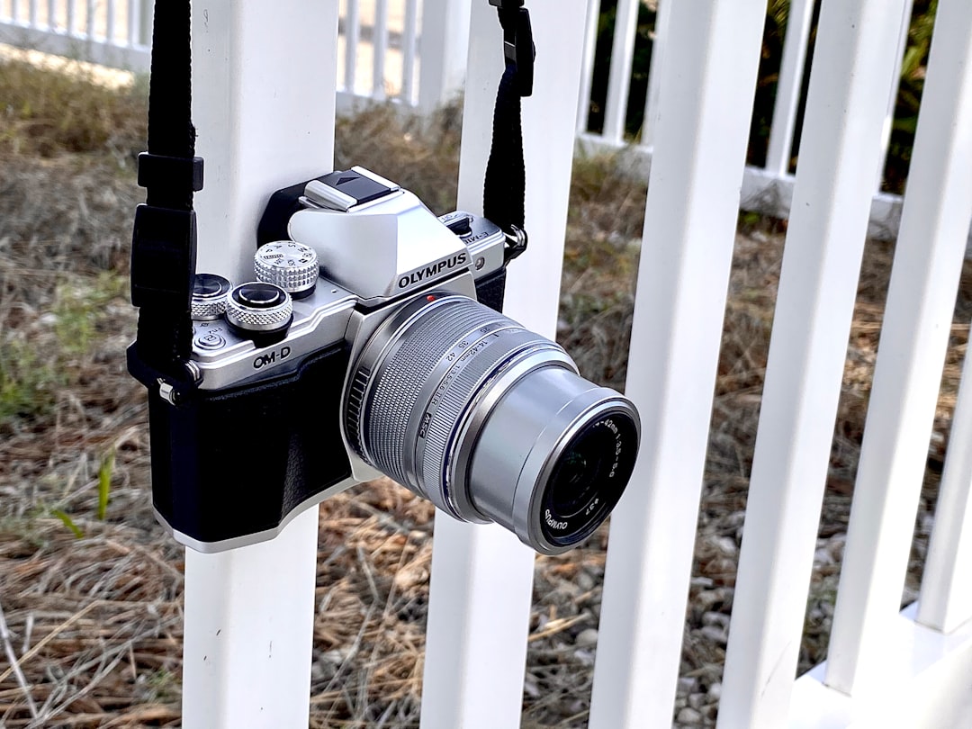 black and silver DSLR camera hanging from a white metal fence