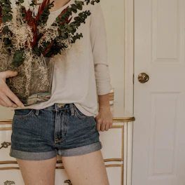 A delivery person handing a beautiful floral arrangement at a cozy home entrance.