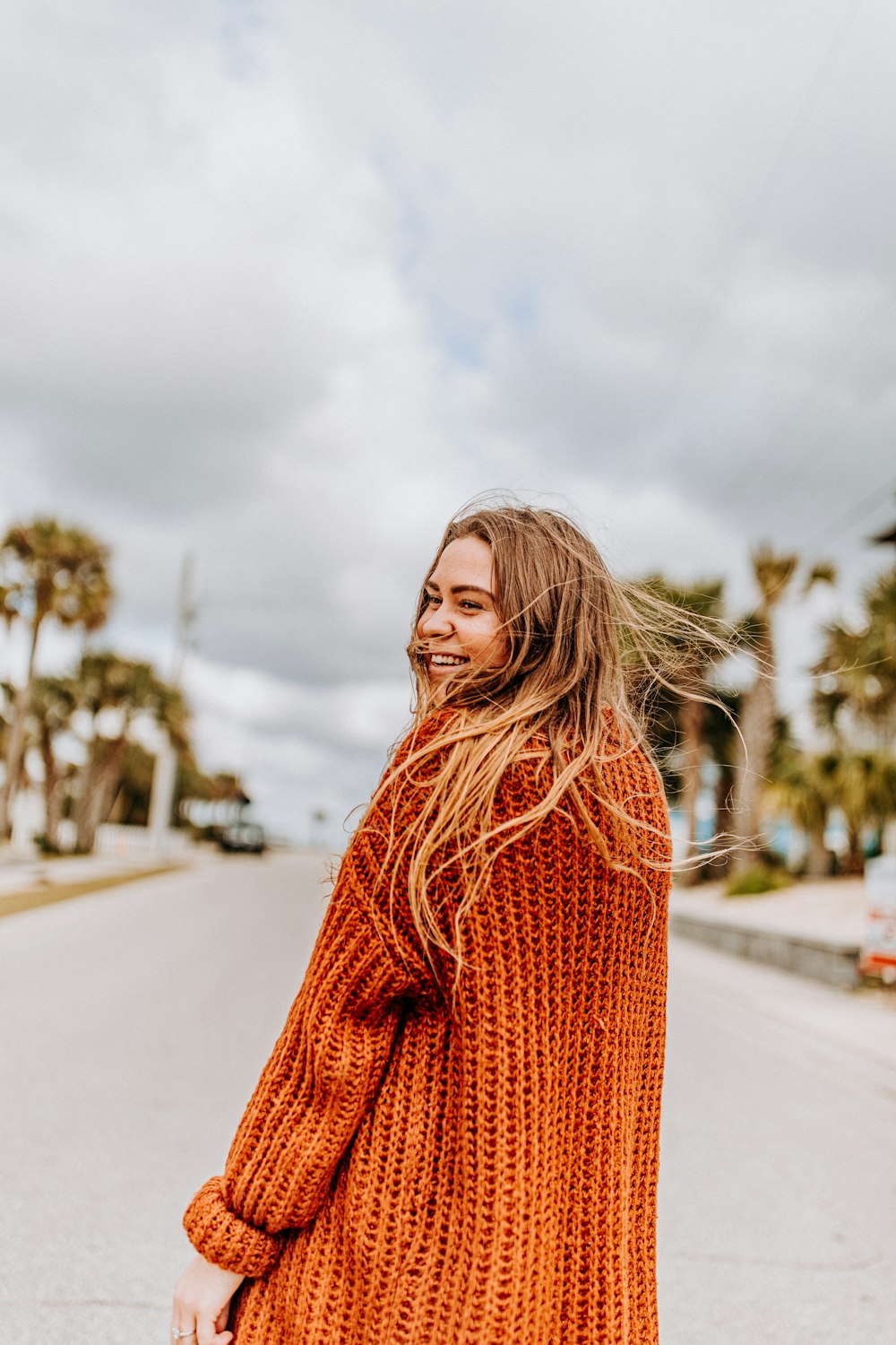 woman smiling and looking over her left shoulder in the middle of the road during day