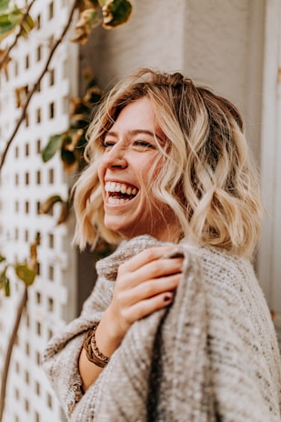 A joyful customer wearing Kerstin Ohrem clothing, smiling in natural light outdoors.