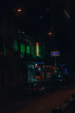 A lively city street with a brightly lit pharmacy sign at dusk.