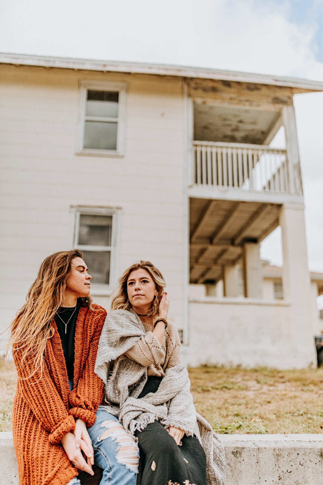 two women sitting in front of house during day