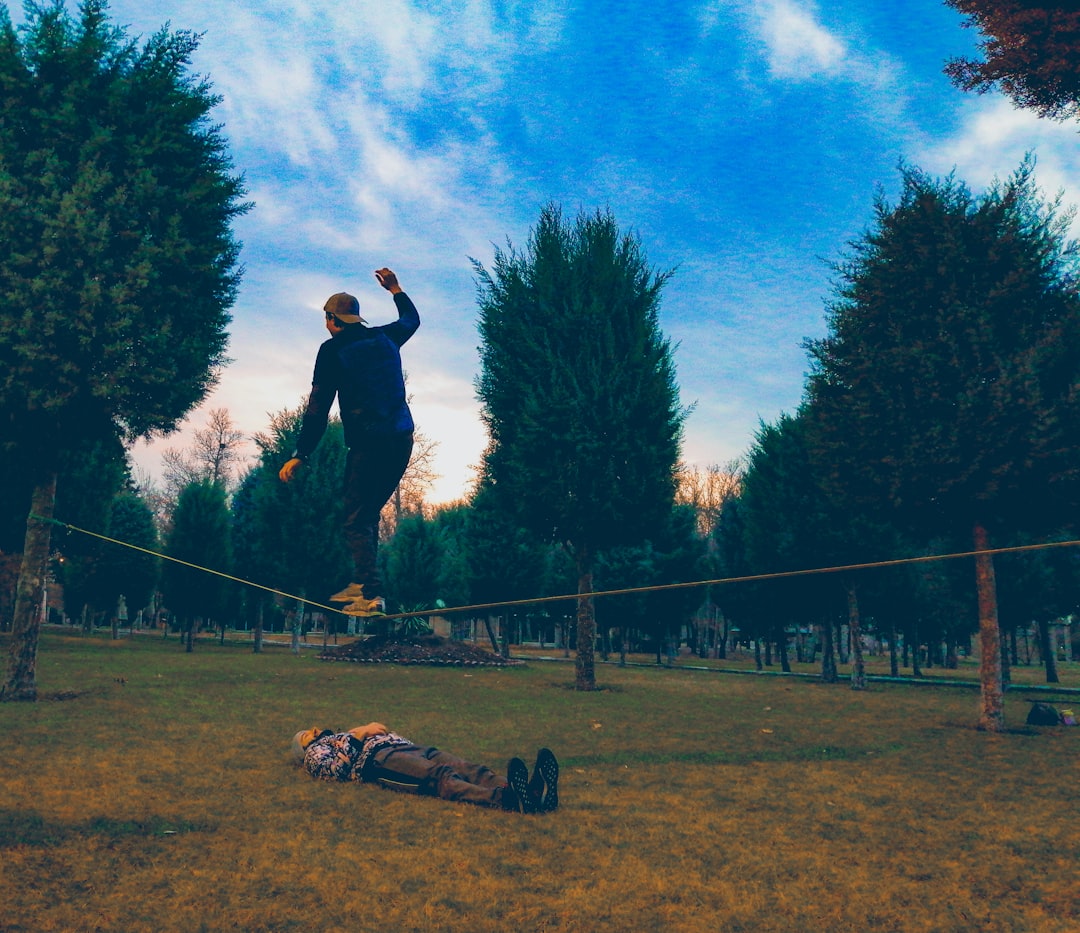 man walking on a string with another man lying under it