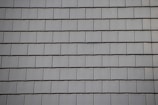 Rows of gray slate tiles are evenly arranged, creating a uniform and structured pattern on a roof surface.