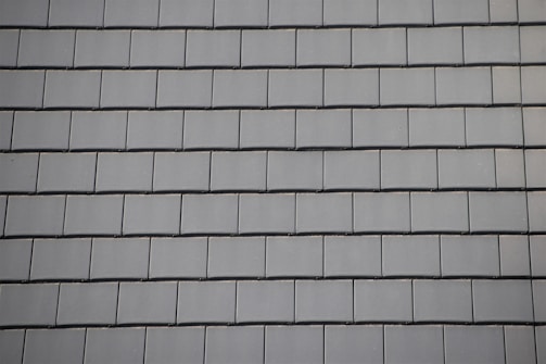 Rows of gray slate tiles are evenly arranged, creating a uniform and structured pattern on a roof surface.