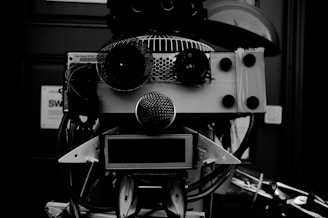 A robotic face crafted from various mechanical and electronic components, including speakers, wires, and metal parts, arranged in a way to resemble facial features.