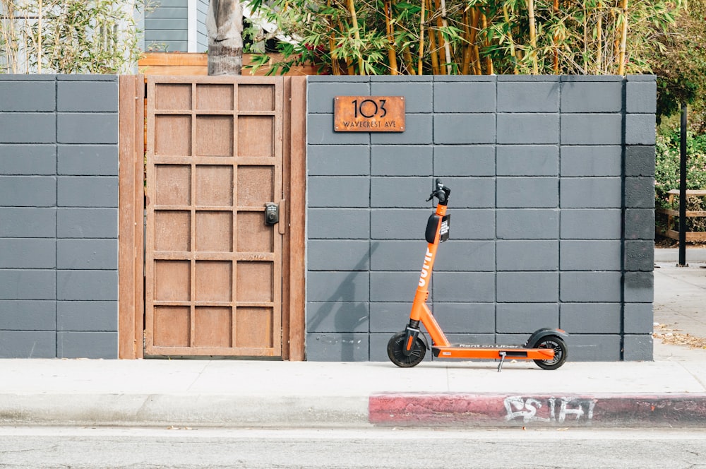 Ein orangefarbener Roller, der vor einem Gebäude geparkt ist