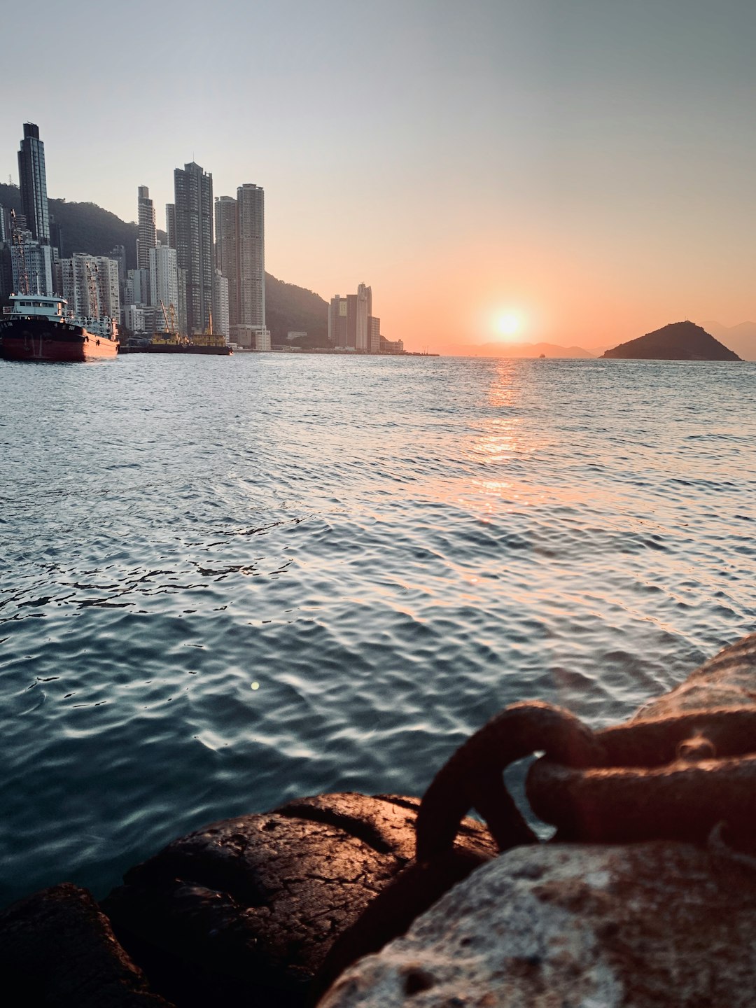 city with high-rise buildings viewing body of water and island during sunrise