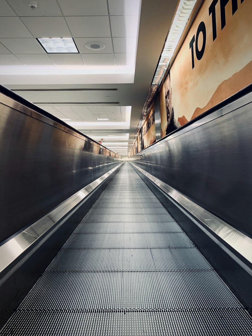 an empty escalator in a building with a sign on the wall