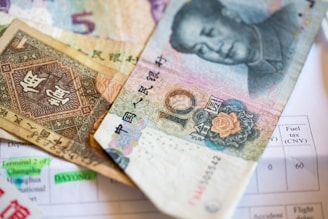 Close-up of hands exchanging RMB currency notes with a blurred shipping container in the background.