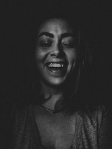 A black and white portrait of a person with closed eyes and a wide smile, creating a joyful and relaxed atmosphere.