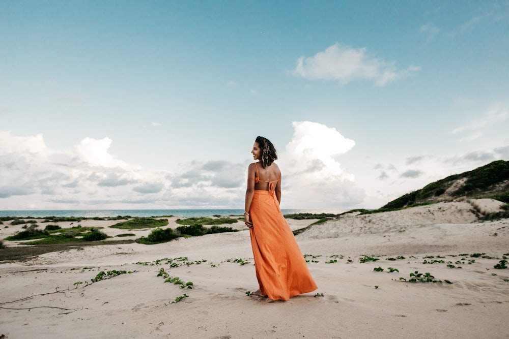 donna in abito arancione in spiaggia