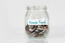 coins in clear glass jar with house fund sign