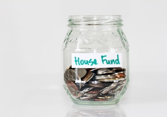 coins in clear glass jar with house fund sign