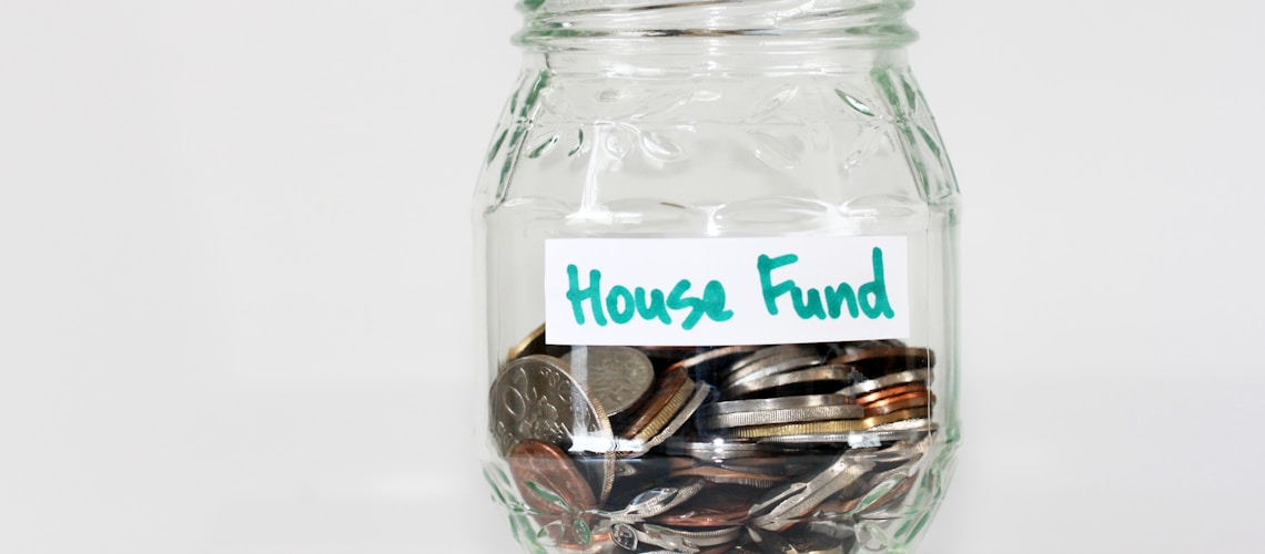 coins in clear glass jar with house fund sign