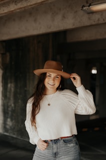 A smiling customer trying on a stylish hat in front of a mirror.