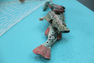 A collection of delicate silver fish sculptures arranged on a rustic wooden table.