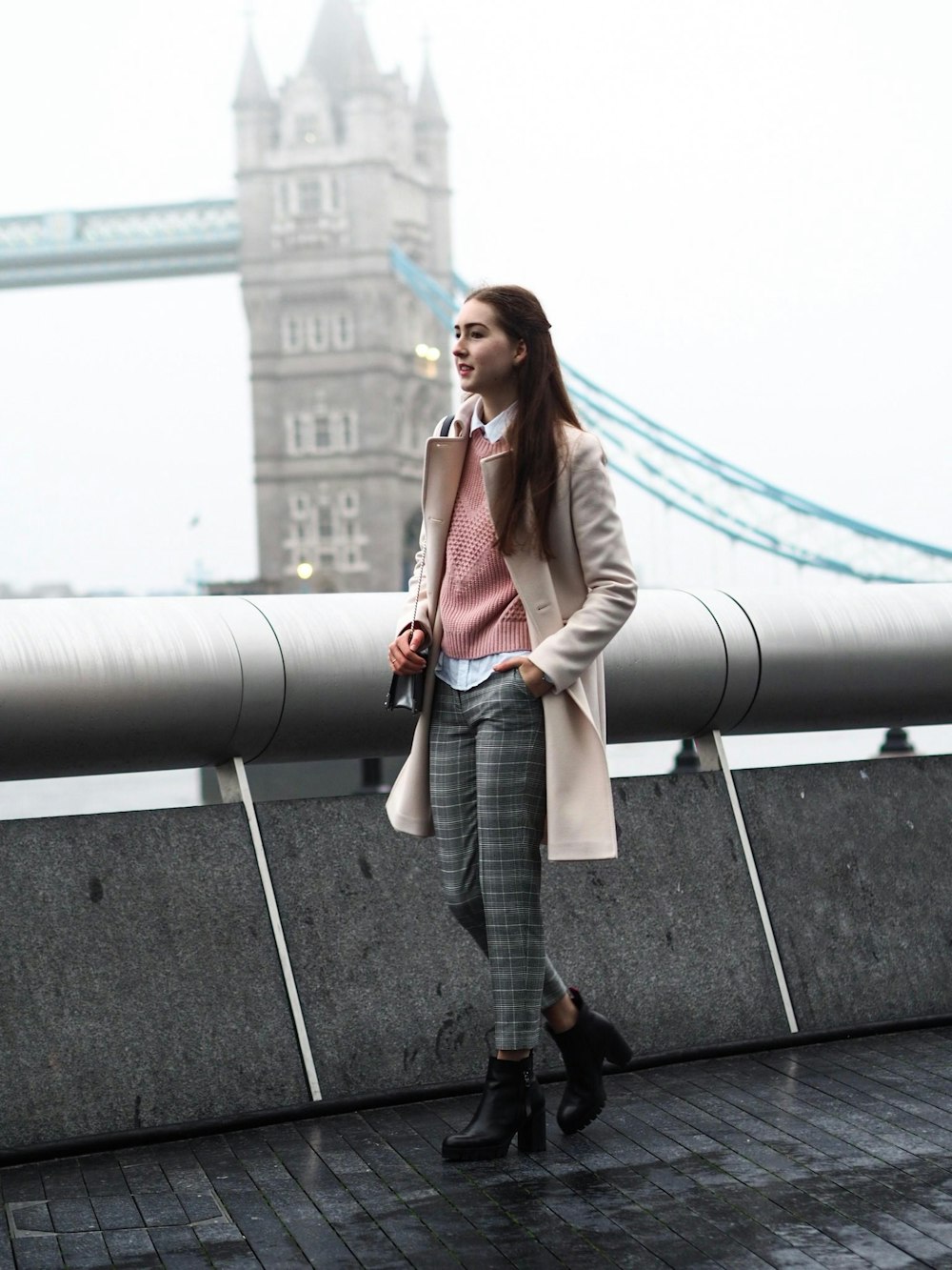 woman in brown overcoat near Tower Bridge