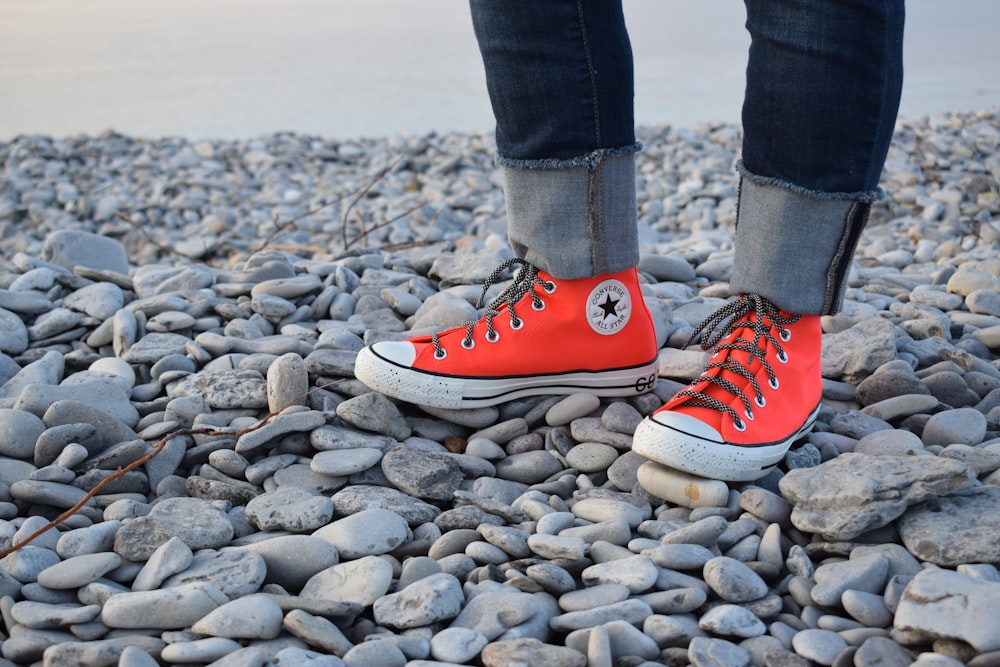 person in blue denim jeans and orange converse all star high top sneakers  standing on rocky photo – Free Petoskey harbor breakwater Image on Unsplash