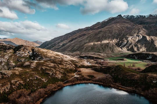 brown mountains and body of water during day in Glendhu Bay New Zealand