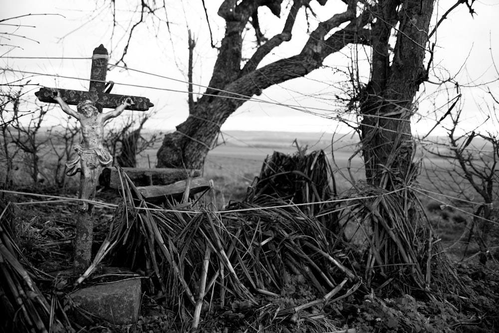 grayscale photography of crucifix near trees