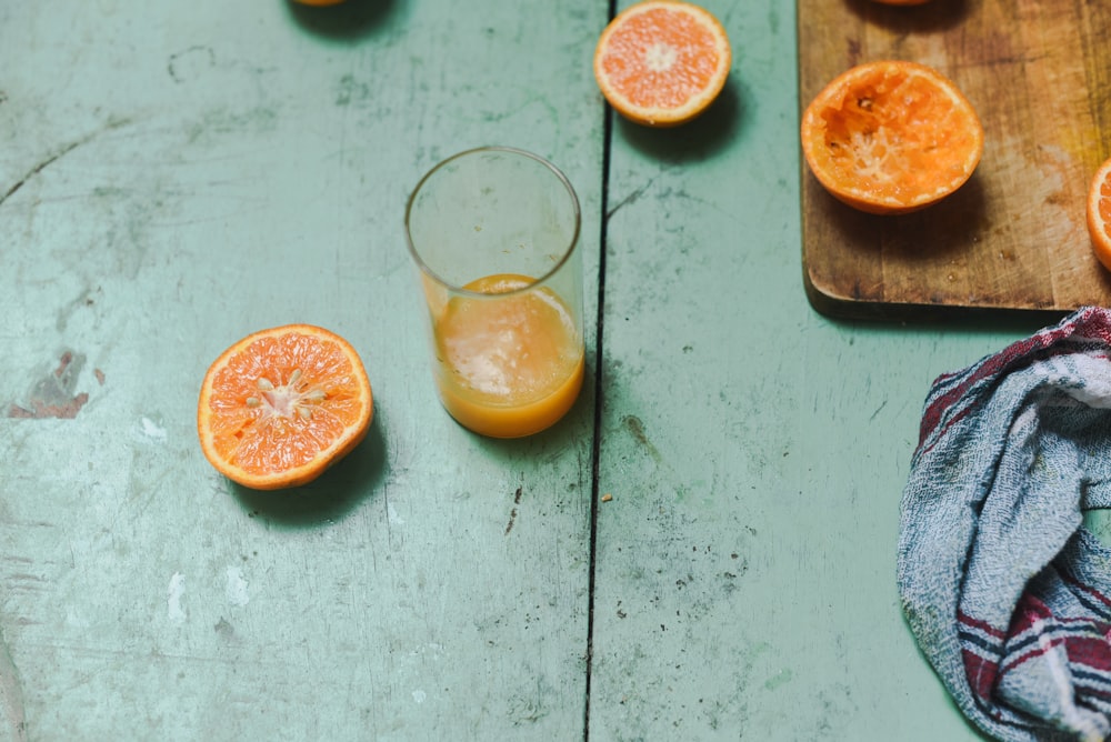 succo d'arancia in vetro vicino all'arancia affettata su tagliere di legno