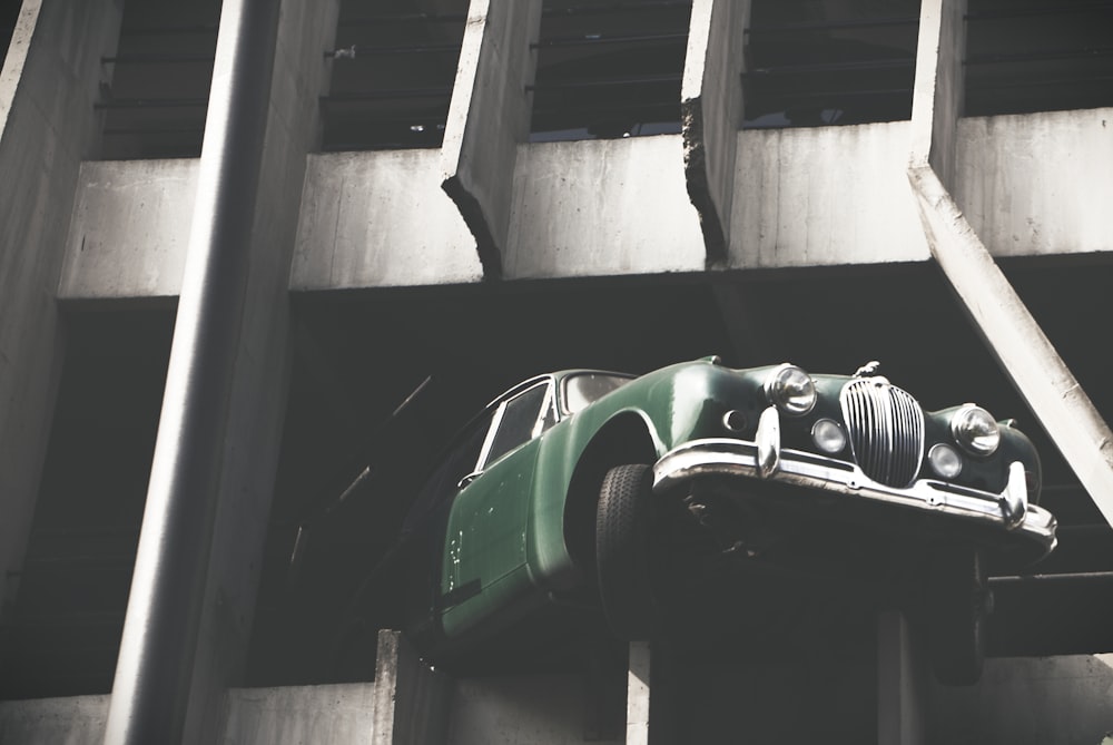 vintage green vehicle on edge of garage area of the building