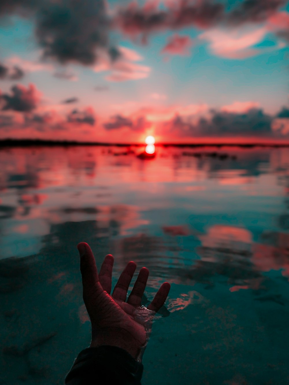 Linke menschliche Hand im Wasser in der Morgendämmerung