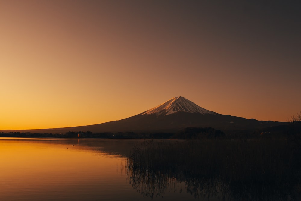 Fotografía de silueta de montaña cerca del lago durante el amanecer