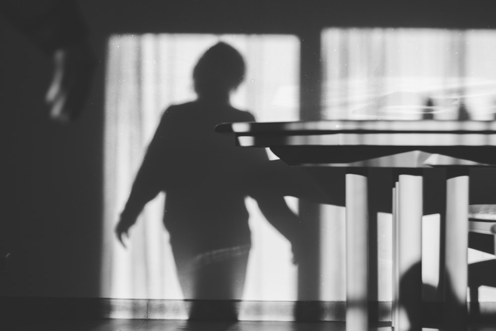 una sombra de una persona parada frente a una mesa