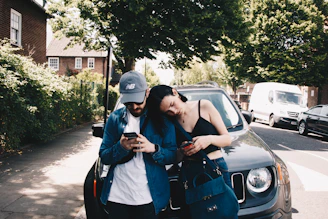 A happy couple standing beside their insured car on a sunny day.