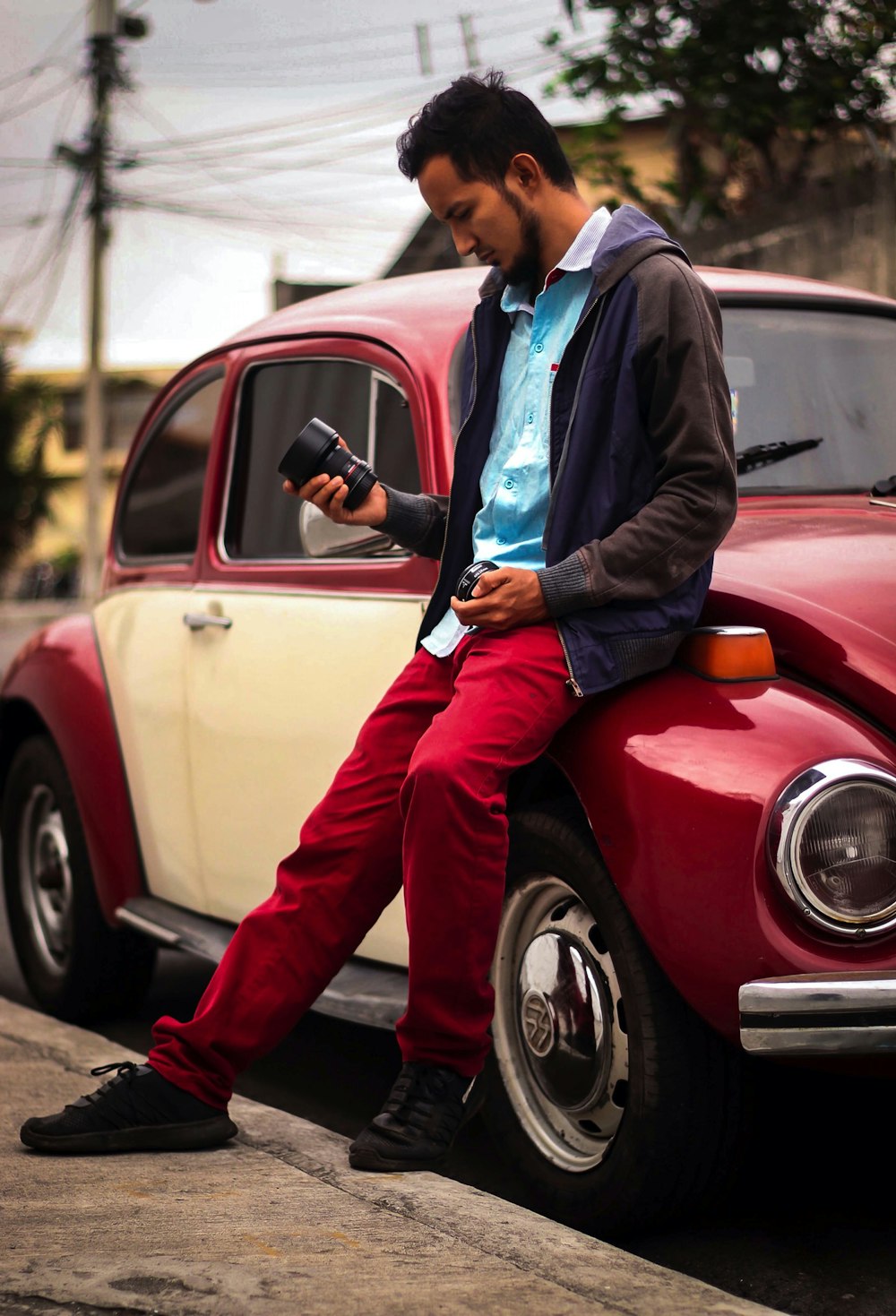a man sitting on the hood of a car looking at his cell phone