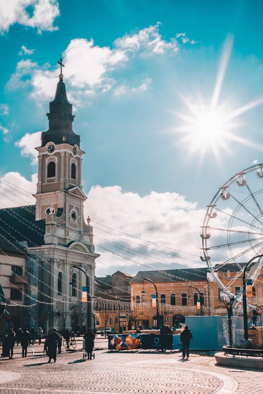 Ferris wheel beside gray concrete church during daytime in Oradea Romania