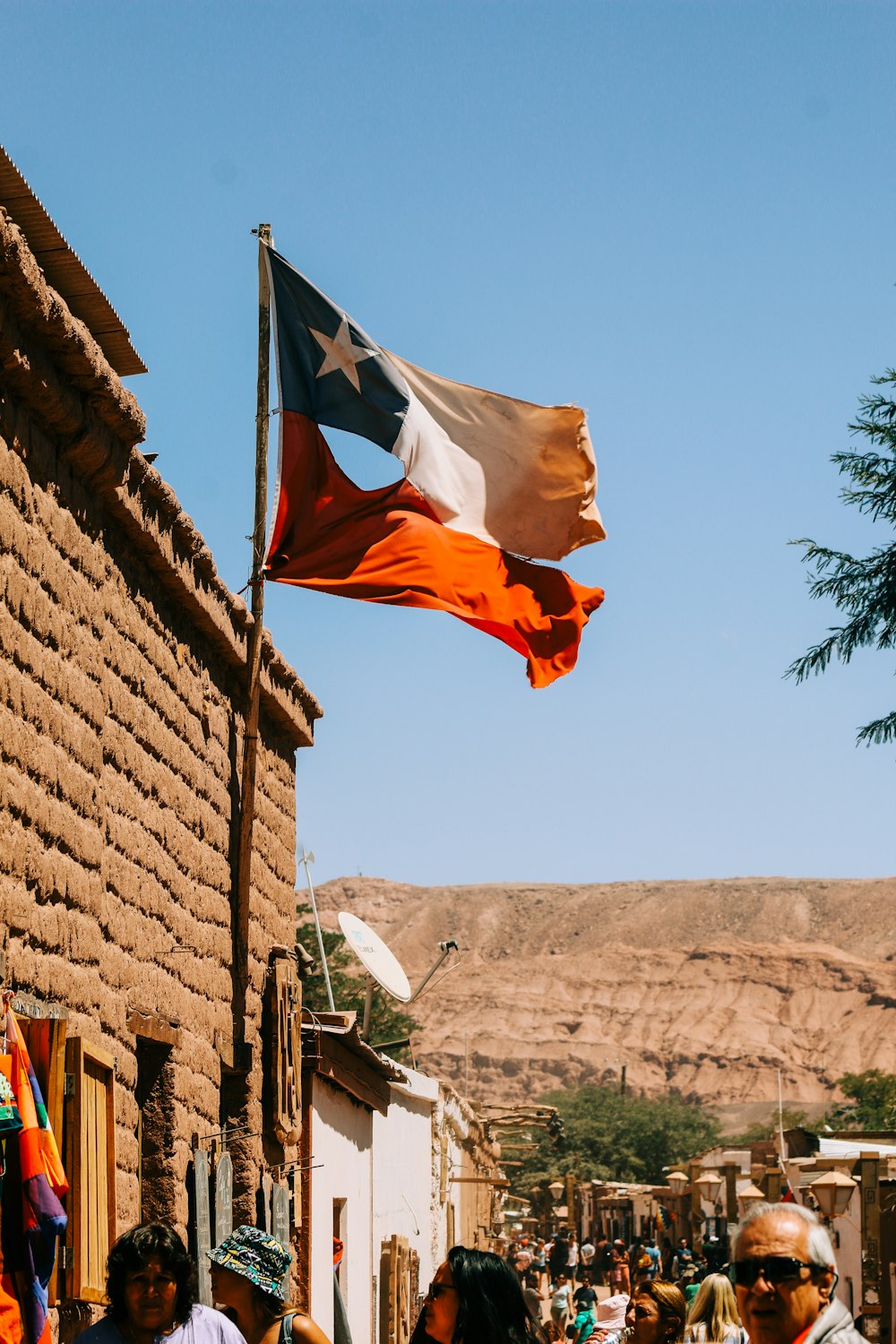 gente caminando cerca de un edificio y bandera de Chile ondeando