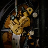 Close-up image of a motorcycle brake caliper with the brand name 'BYBRE' prominently displayed. The caliper is attached to the wheel using several bolts, and the brake disc is partially visible through the spokes of the wheel.
