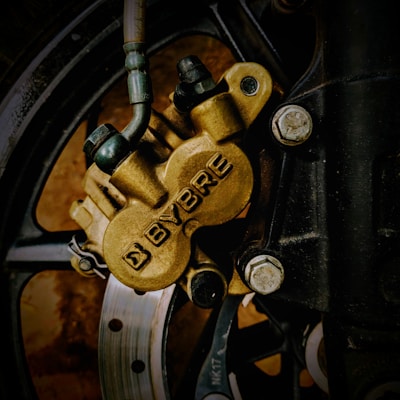 Close-up image of a motorcycle brake caliper with the brand name 'BYBRE' prominently displayed. The caliper is attached to the wheel using several bolts, and the brake disc is partially visible through the spokes of the wheel.