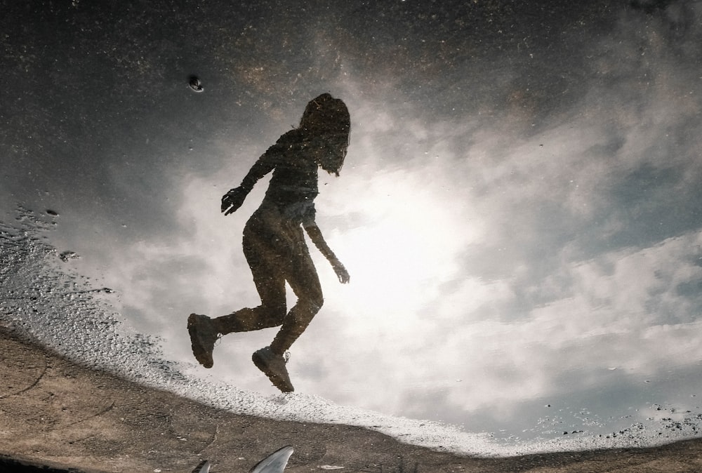 silhouette of person jumping on snow covered ground under starry night