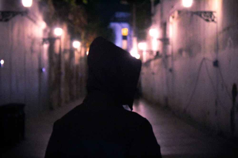 person in hoodie standing on lighted street