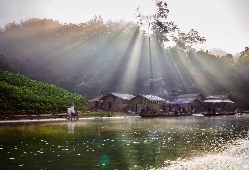 brown wooden houses near river surrounded with green trees during daytime