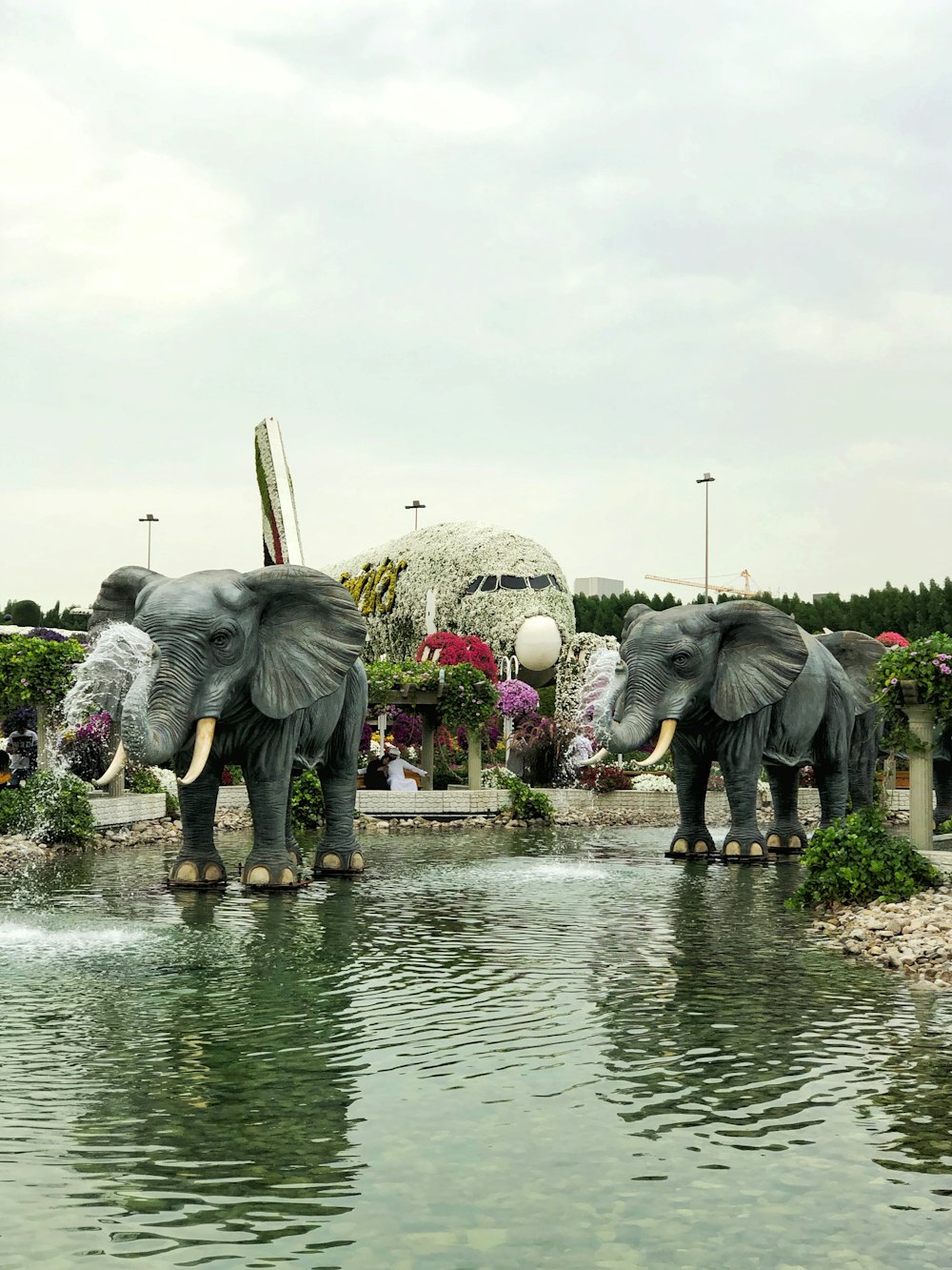 two gray elephants statue on pond during daytime