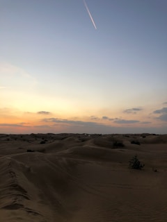 A serene desert landscape at sunset with rolling sand dunes.