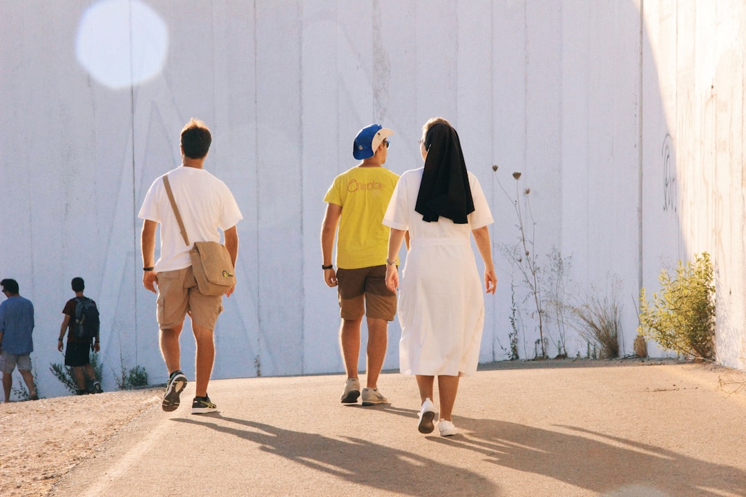 shallow focus photo of person in white dress, Nun and seminarians walking along the wall