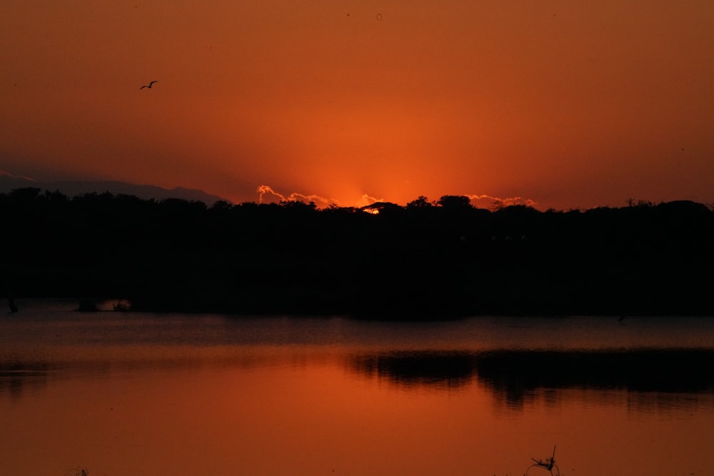 silhouette of mountain reflected on body of water