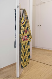 yellow and black shirt hanging on white wooden door