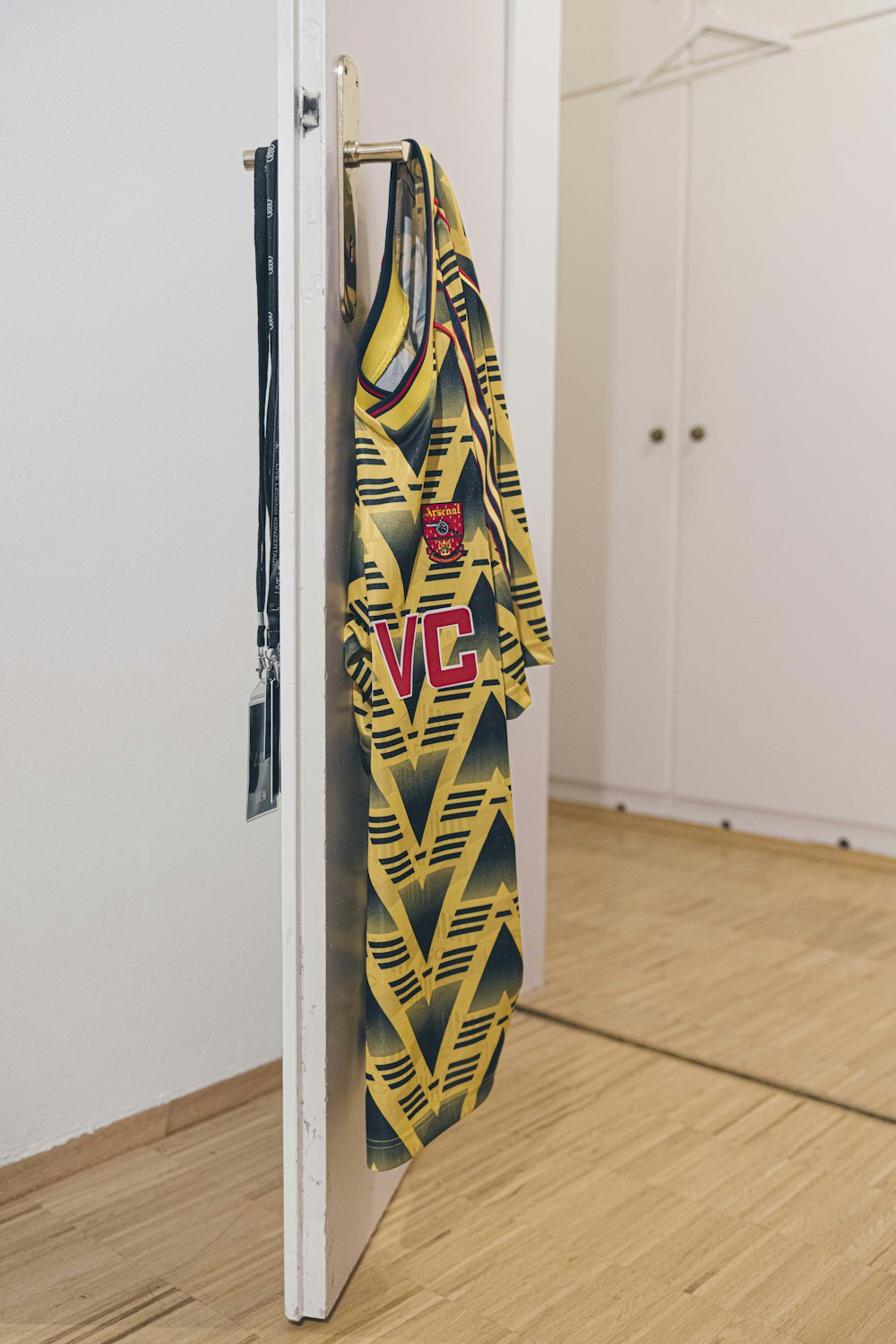 yellow and black shirt hanging on white wooden door