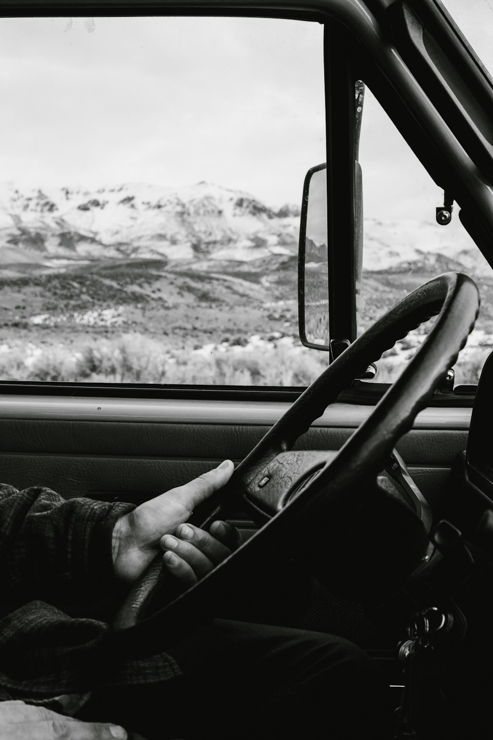 grayscale photo of man driving vehicle