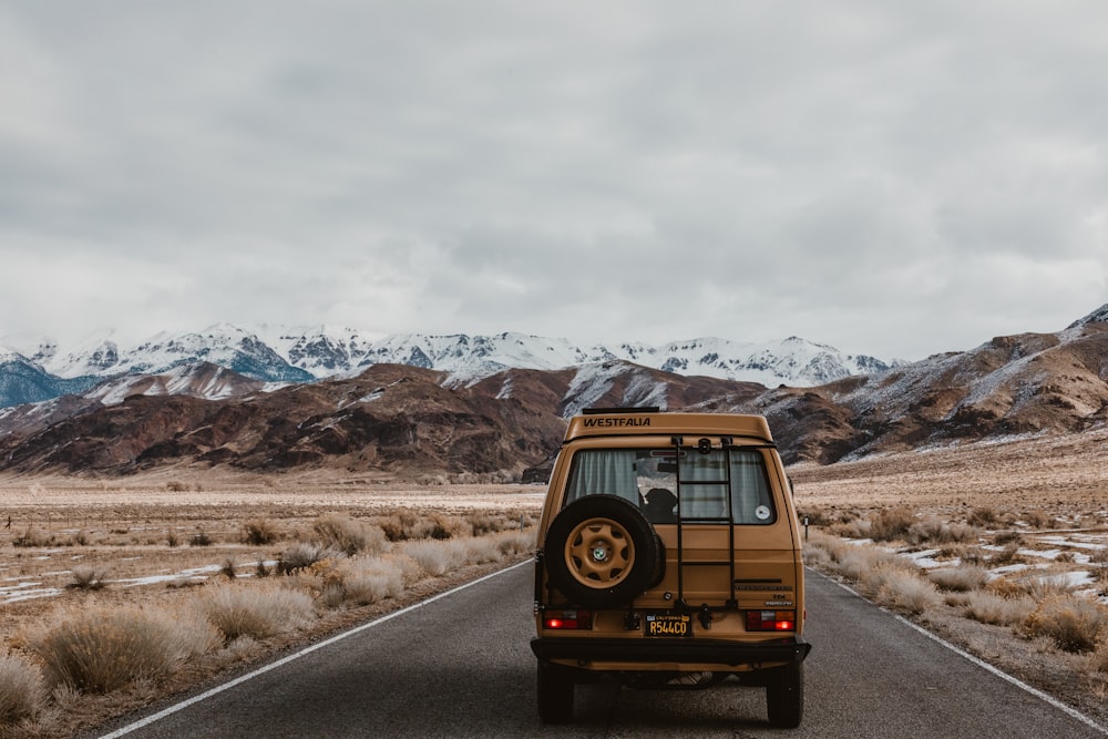 brown vehicle on road under white sky