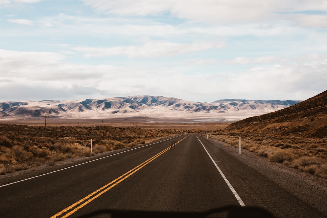 road near mountains under cloudy sky