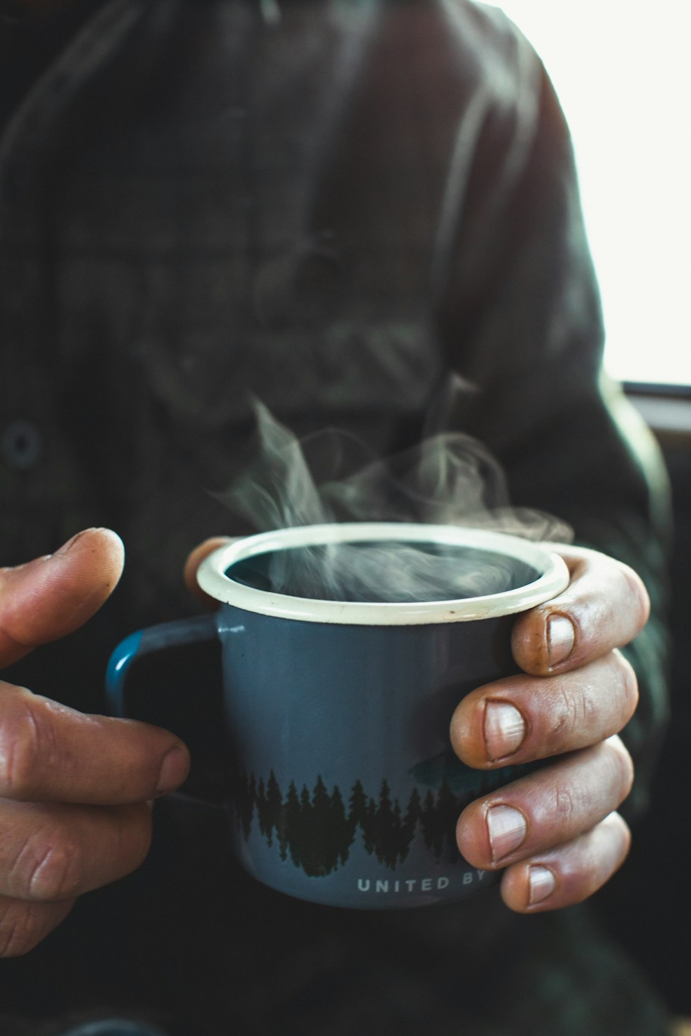 shallow focus photo of person holding blue ceramic mug